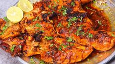 a plate full of chicken with lemon wedges and parsley