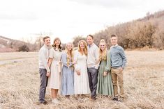 a group of people standing next to each other in a field with tall dry grass