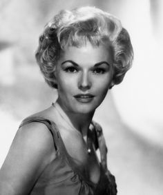 a black and white photo of a woman with blonde hair wearing a halter top