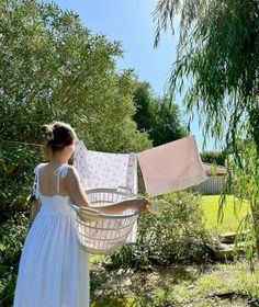 a woman in a white dress holding a laundry line