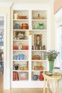 an open bookcase filled with books in a living room next to a wooden table