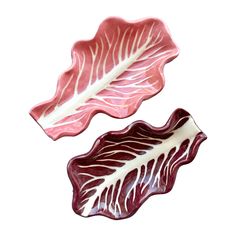 two red and white leaf shaped dishes sitting next to each other on a white surface