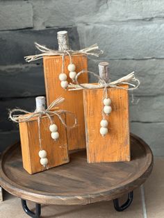 three wooden blocks with twine and beads tied to them sitting on a round table