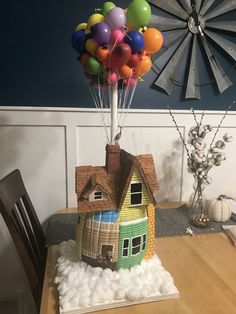 a house with balloons on top of it sitting in the middle of a dining room