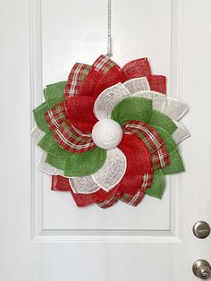 a red and green christmas wreath hanging on a white door