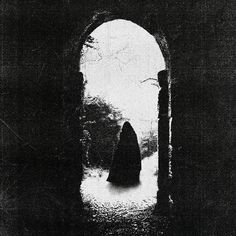 a black and white photo of a person standing in an archway