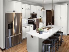 a kitchen with white cabinets, stainless steel appliances and an island that has stools