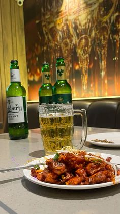 there is a plate of food and two beer bottles on the table in front of it