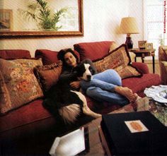 a woman is sitting on the couch with her dog