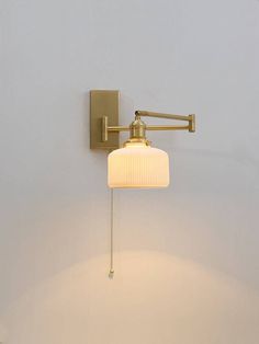 a wall light with a white shade hanging from it's side in a room