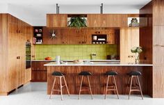 an open kitchen with bar stools and green tile backsplash, surrounded by wooden cabinets