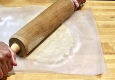 a person rolling dough on top of a wooden table