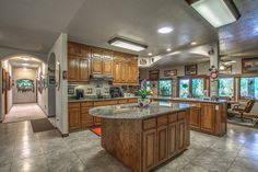 a large kitchen with wooden cabinets and granite counter tops, along with an island in the middle