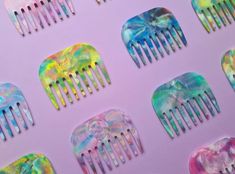 six different colored combs are arranged on a pink background with multicolored designs