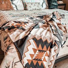 a bed covered in an orange and black comforter sitting next to a night stand