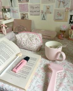 an open book on a table next to a coffee cup and pink hairdryer