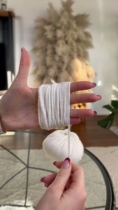 a woman's hand with white yarn wrapped around her thumb and fingernails