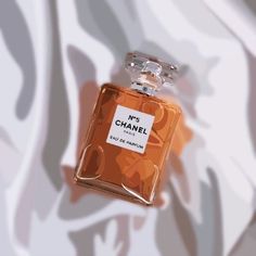 an orange chanel perfume bottle on a white and grey background with the words, it's chanel