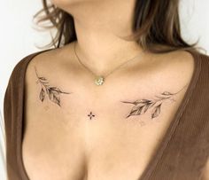 a woman's chest with two leaves and a cross tattoo on her left side