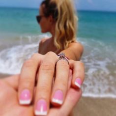 a woman holding onto her engagement ring on the beach