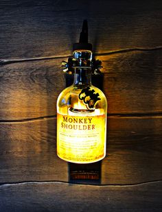 a bottle of monkey shoulder sitting on top of a wooden table next to a light