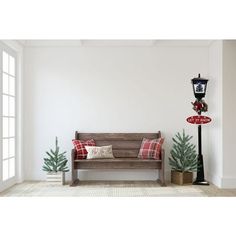 a wooden bench sitting in the middle of a room next to a lamp post and christmas trees