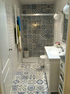 a bathroom with blue and white tile on the floor, shower stall door open to reveal a sink