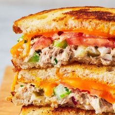 a close up of a sandwich with meat and vegetables on toasted bread, cut in half