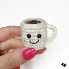 a small crocheted coffee cup with a smiling face on it's side