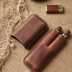 two brown leather pouches sitting on top of a table next to an empty lighter