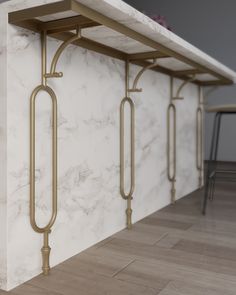 a white marble counter top with gold metal handles and bars on the wall next to it