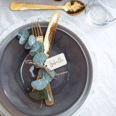 a table setting with place cards, silverware and greenery on the plate for guests to eat