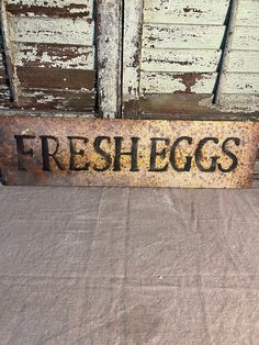 a sign that says freshegs on it in front of a wooden door with peeling paint