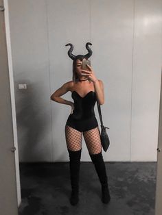 a woman in fishnet stockings taking a selfie with her cell phone while wearing devil horns