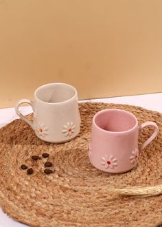 two coffee cups sitting on top of a place mat