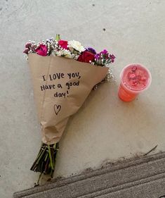 a bouquet of flowers sitting next to a plastic cup on the side of a building