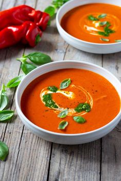 two bowls of tomato soup with basil garnish