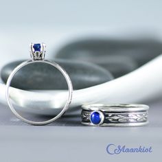 two silver rings with blue stones in the middle and one white ring sitting next to each other