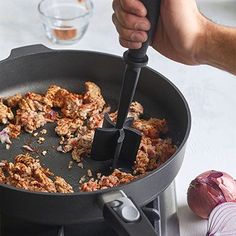 someone is frying food in a skillet on the stove with an onion wedge