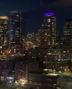 the city skyline is lit up at night, with skyscrapers in the foreground