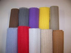 six rolls of colored knitted fabric lined up in rows