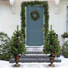 a blue front door surrounded by christmas trees and potted plants