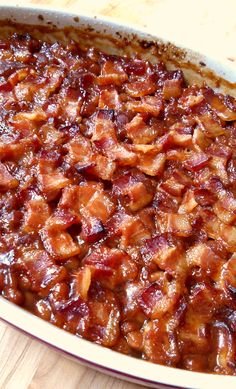 a casserole dish filled with bacon on top of a wooden table