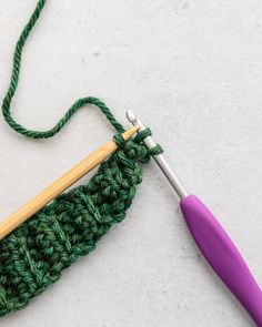 the crochet hook is next to an object that looks like a knitting needle