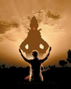 the silhouette of a person standing in front of a large statue with his hands up