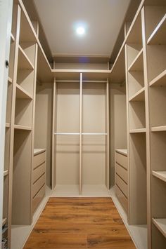 an empty walk in closet with wooden flooring and shelves on the wall above it