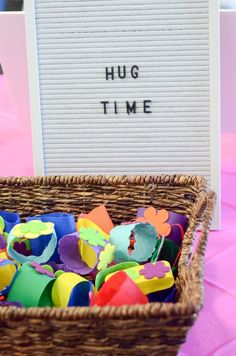 a basket filled with lots of different colored pieces of paper next to a sign that says hug time