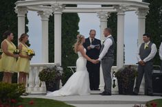 a bride and groom holding hands at their wedding ceremony in front of an outdoor gazebo