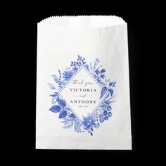 a white paper bag with blue flowers and the words victoria & anthony printed on it