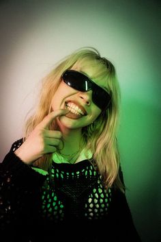 a woman wearing sunglasses making a silly face with her fingers and mouth open while posing for the camera